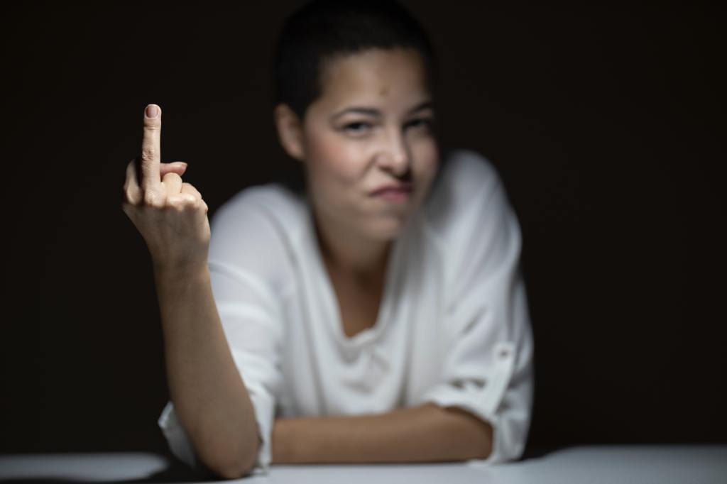 Angry girl with short hair giving the finger to the camera
